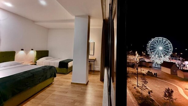 A modern hotel room with a large window overlooking a Ferris wheel. - Hotel Republika Berat (Velabisht)