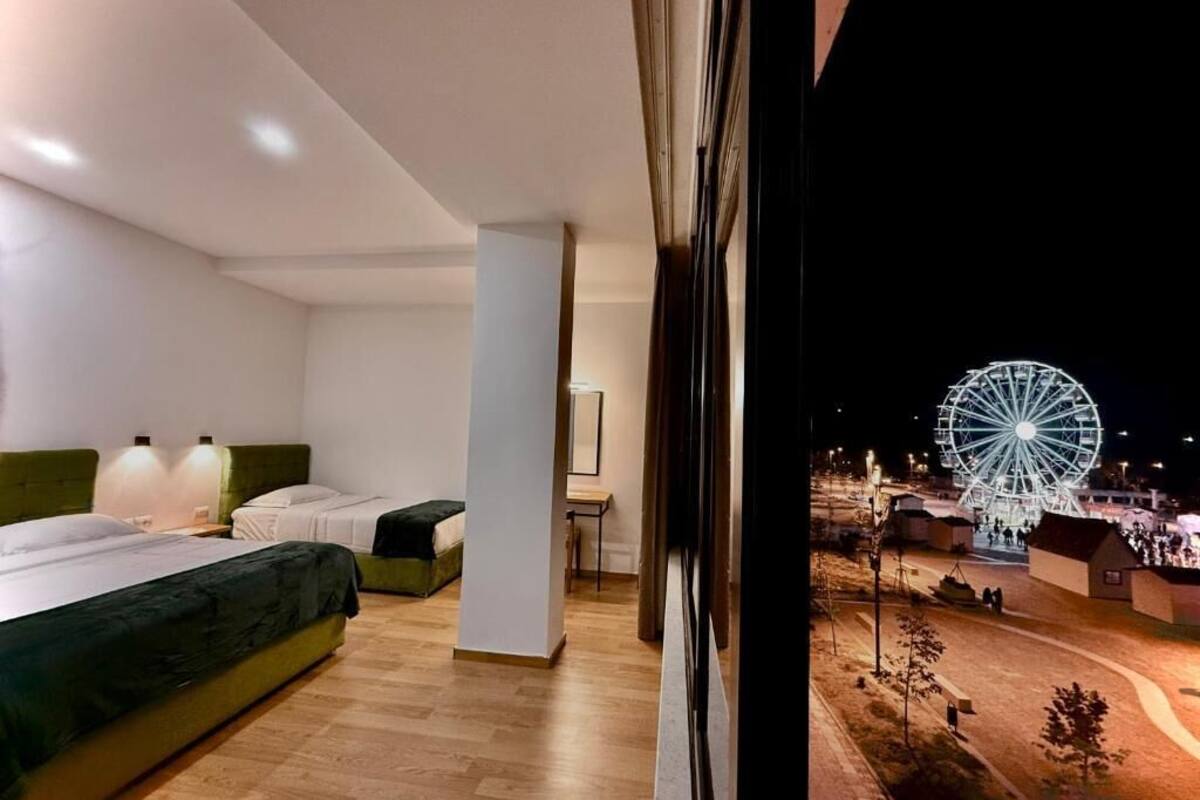 Habitación de hotel moderna con un gran ventanal que da a una noria.