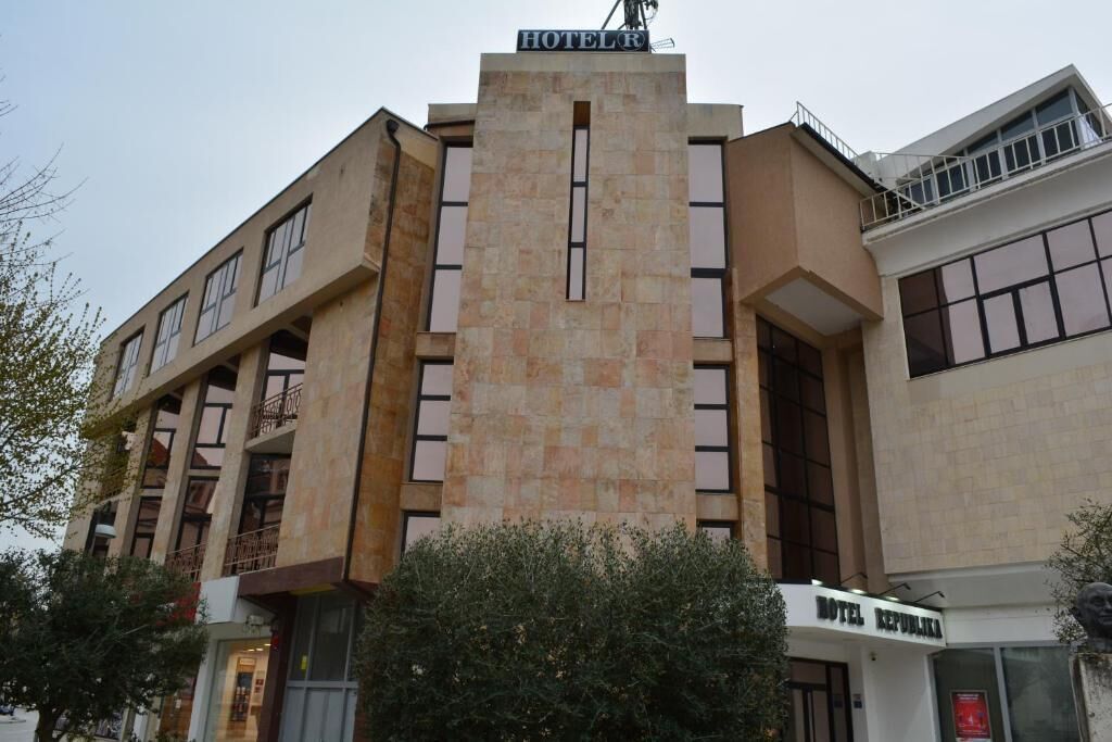 Um hotel com uma torre central imponente, várias varandas e uma placa indicando ser um hotel.