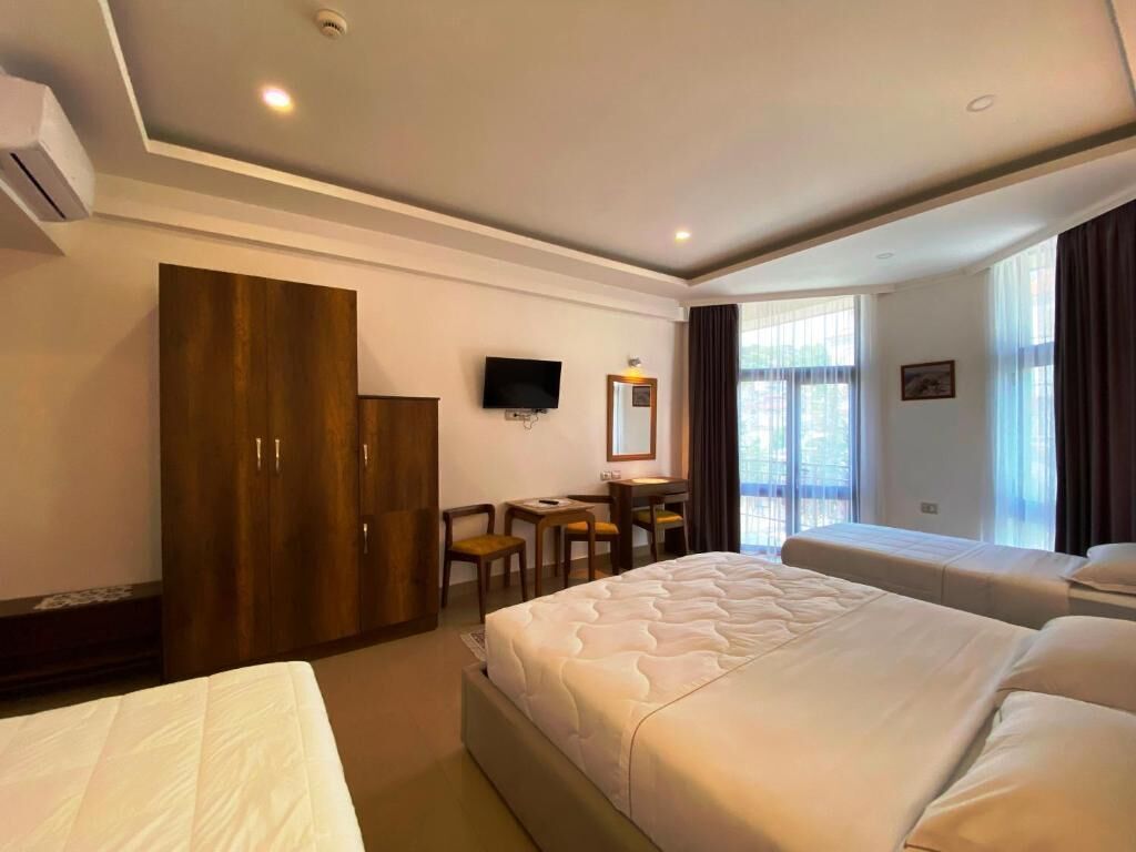 Habitación de hotel con dos camas, un escritorio, un televisor y un armario.