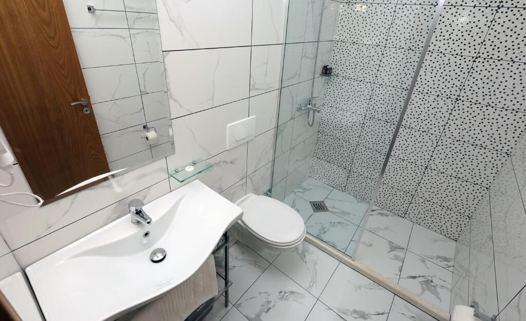 Un bagno moderno con lavabo in marmo, toilette e cabina doccia in vetro.