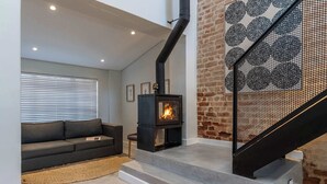 A modern living room with a fireplace, a staircase, and a sofa. - Views, Fireplace, Sea Point - Mnt Nelson Townhouse (Cape Town)