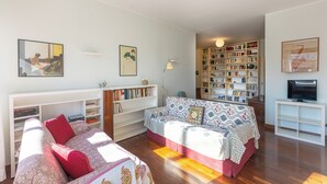 Een gezellige woonkamer met een zithoek, een boekenkast en een televisie.