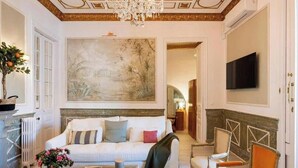 A well-lit living room with a white sofa, a coffee table, and a painting on the wall. - Spacious 5-bedroom apartment in charming Barcelona with AC (Barcelona)