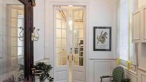 A room with a wooden ceiling, a chandelier, a door leading to another room, a framed picture on the wall, and a round table with chairs. - Spacious 5-bedroom apartment in charming Barcelona with AC (Barcelona)