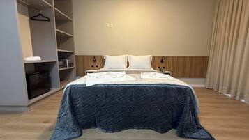 Una habitación de hotel moderna con una cama grande, un armario y una mesita de noche.