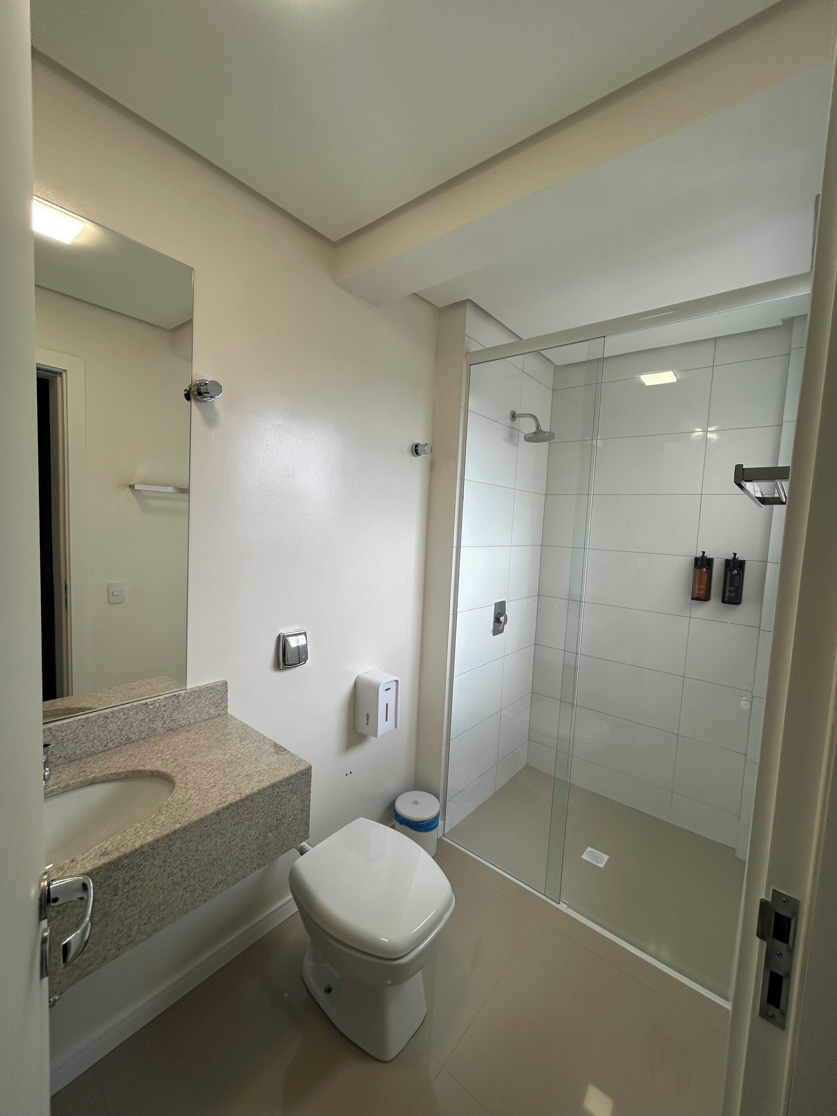 A modern bathroom with a toilet, sink, and glass-enclosed shower.
