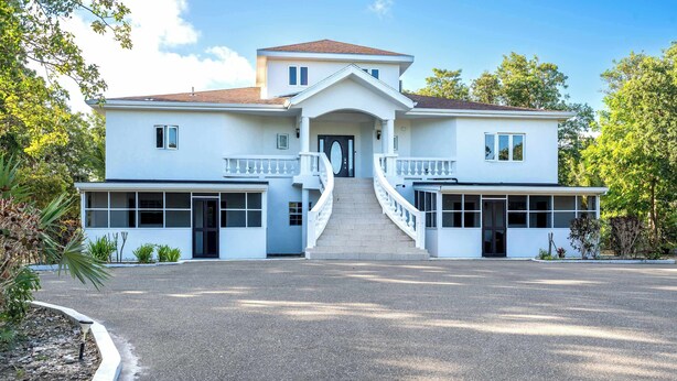A two-story building with a central entrance, a staircase, and a driveway. - Peaceful Island Retreat w/ Private Patio + Parking (Leeward Settlement)