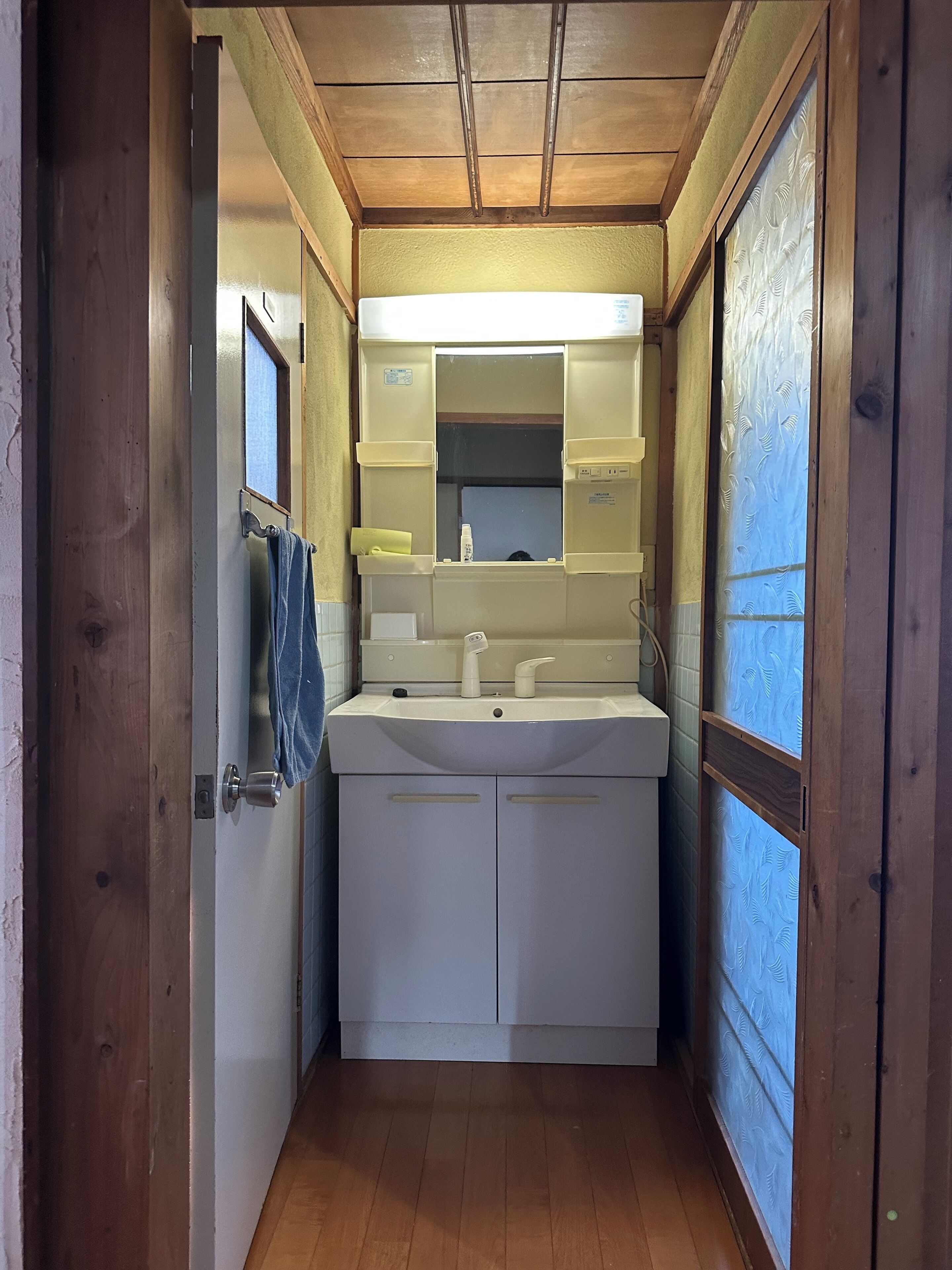 Une petite salle de bain avec un plafond en bois, un lavabo blanc et un miroir au-dessus.