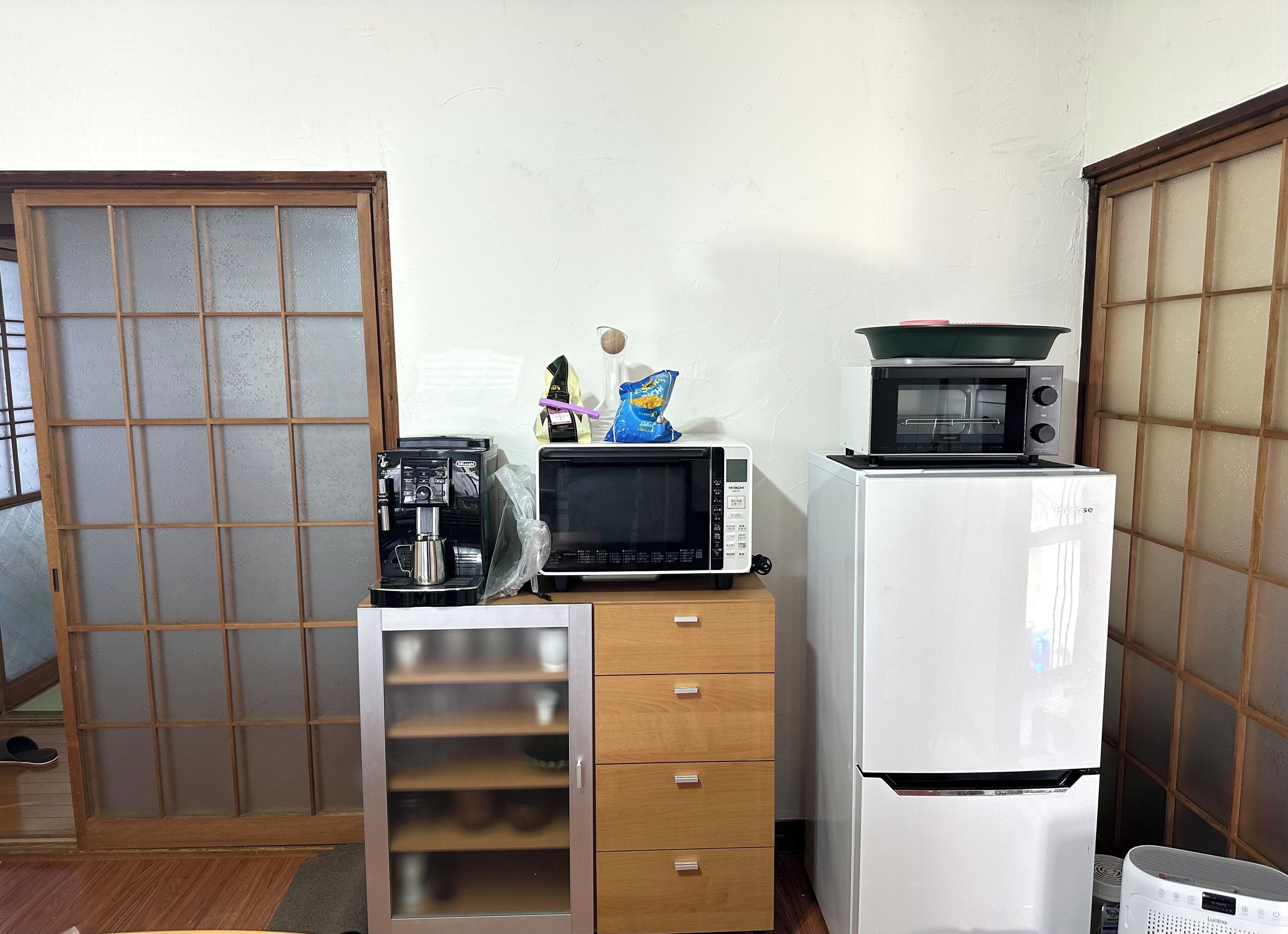 Une cuisine compacte équipée d’une machine à café, d’un four à micro-ondes et d’un réfrigérateur.