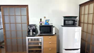 Une cuisine compacte équipée d’une machine à café, d’un four à micro-ondes et d’un réfrigérateur.