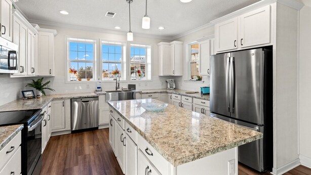 A modern kitchen with white cabinetry, stainless steel appliances, granite countertops, and pendant lighting. - Beach House - C Shucker by PHG (Mexico Beach)