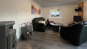 A modern living room with a fireplace, leather sofas, a dining table, and a large window with a view. - Quiet & close to the city (Chemnitz)