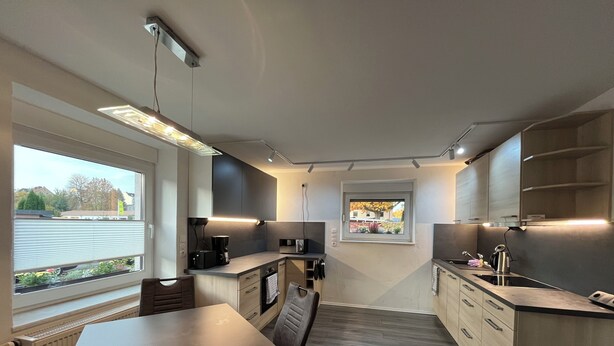 A modern kitchen with a dining area, featuring a built-in microwave, coffee maker, and a window with a view of the outside. - Quiet & close to the city (Chemnitz)