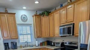 A kitchen with wooden cabinets, a central island with stools, a stainless steel refrigerator, and a microwave. - KLTD1  Klonteska Manor  An unforgettable mountain getaway! (Beech Mountain)