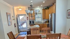 A dining area with a wooden table and chairs, a patterned rug, and a kitchen in the background. - KLTD1  Klonteska Manor  An unforgettable mountain getaway! (Beech Mountain)