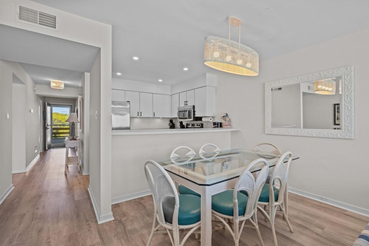A modern kitchen with white cabinets, a microwave, and a hanging light fixture.