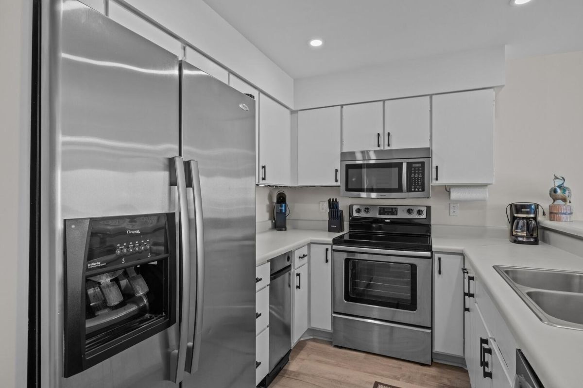 A modern kitchen with stainless steel appliances, including a refrigerator, microwave, oven, and coffee maker.