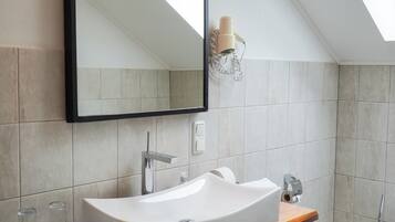 Een moderne badkamer met een vrijstaand wastafelmeubel, een grote spiegel en een dakraam.