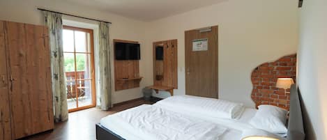 Un dormitorio con cama, armario de madera, escritorio y pared de ladrillo.