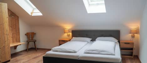 Un dormitorio con una cama grande, tragaluces, suelo de madera y lámparas de noche.