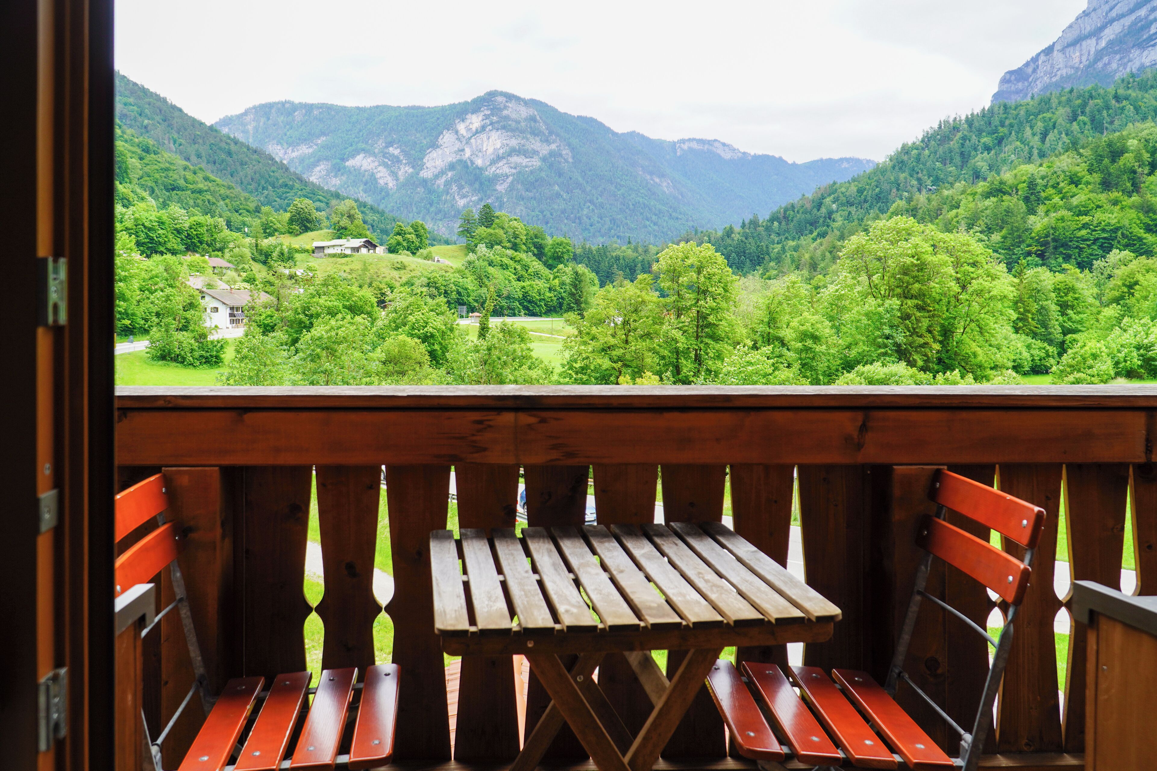 A wooden deck with a table and benches overlooking a mountainous landscape.