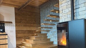 A modern interior with a stone wall, wooden staircase, and a wood-burning stove. - Chalet Altea View: panoramic Lake Como, 8 places, garden and barbecue. (Mello)