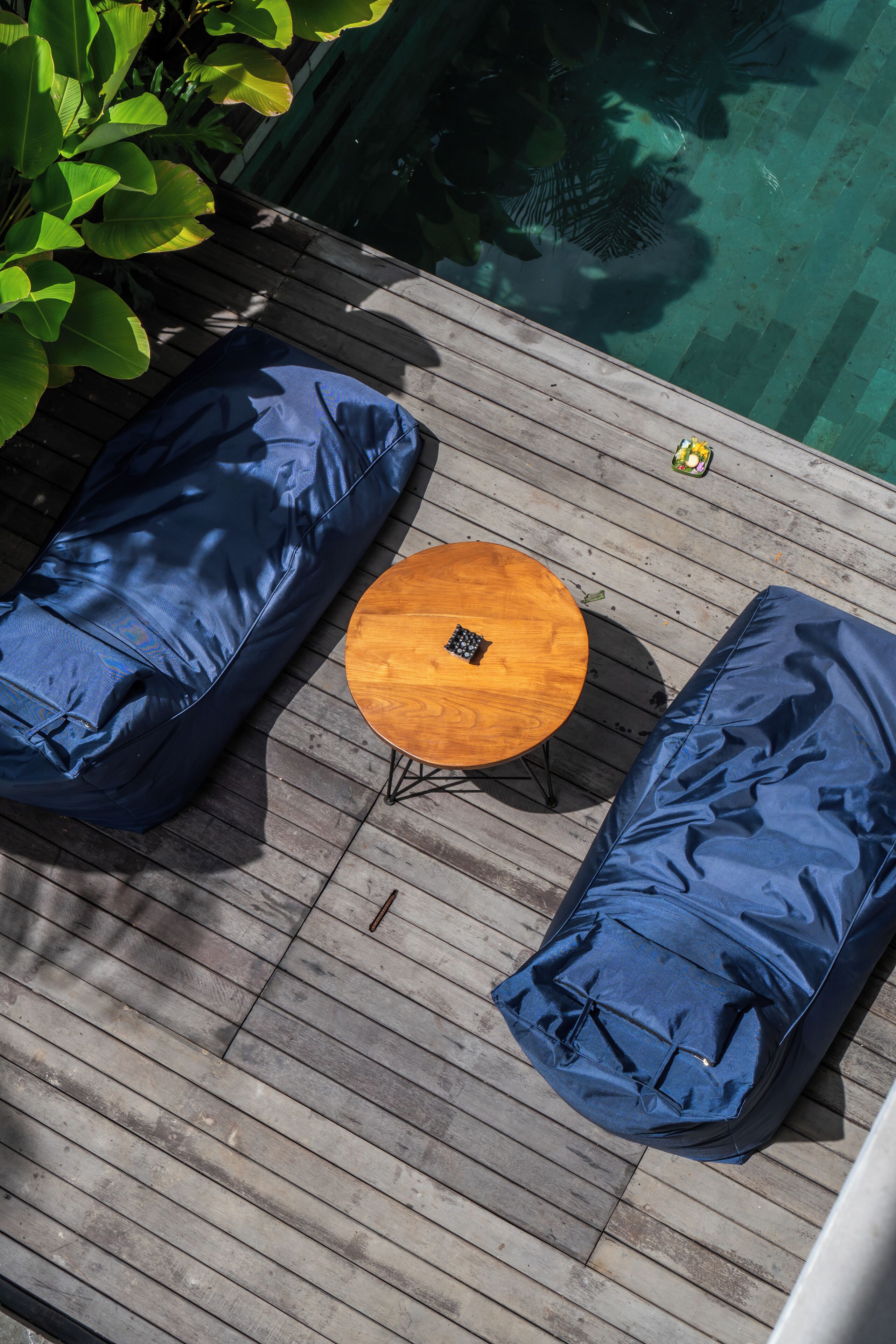 A wooden deck with blue cushioned seating and a round wooden table.