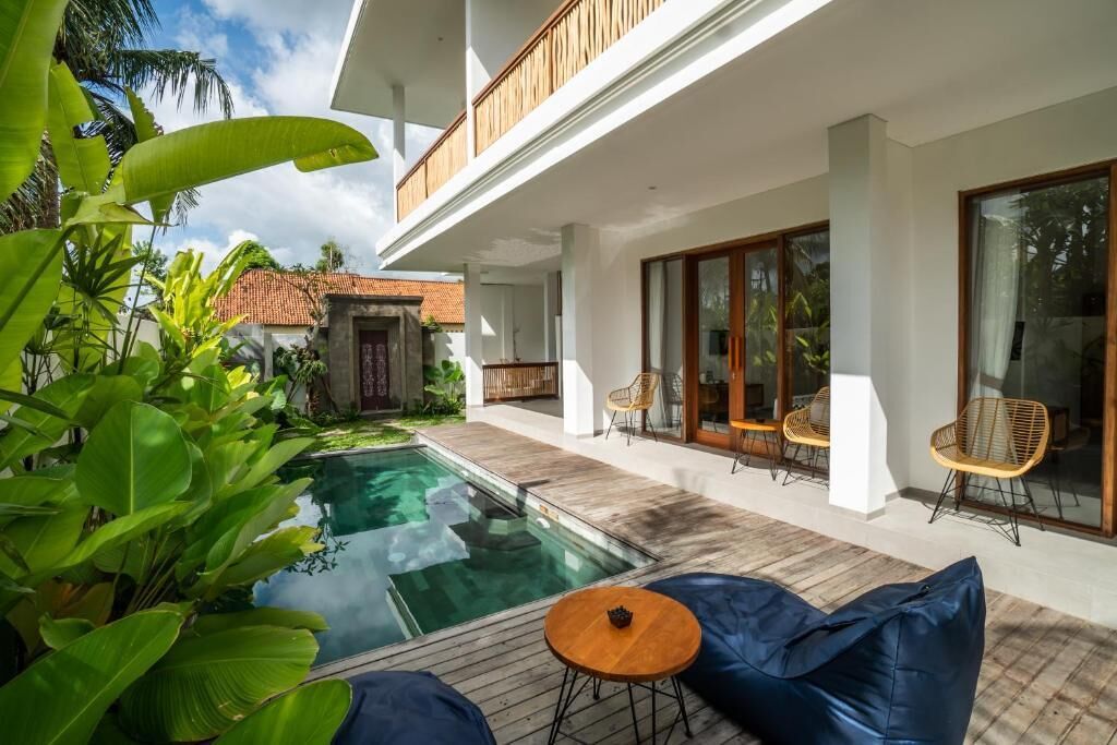 A modern house with a swimming pool, outdoor seating, and lush greenery.