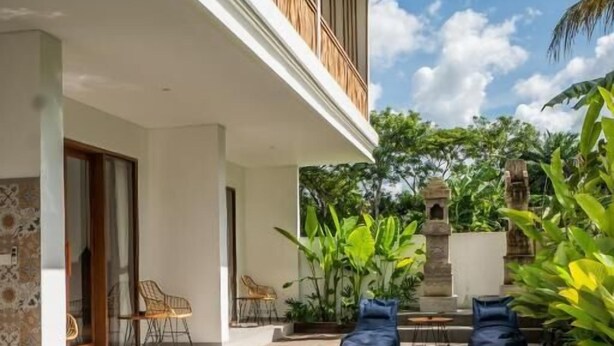 A poolside area with a wooden deck, lounge chairs, and a stone structure. - Kemari Ubud (Ubud)