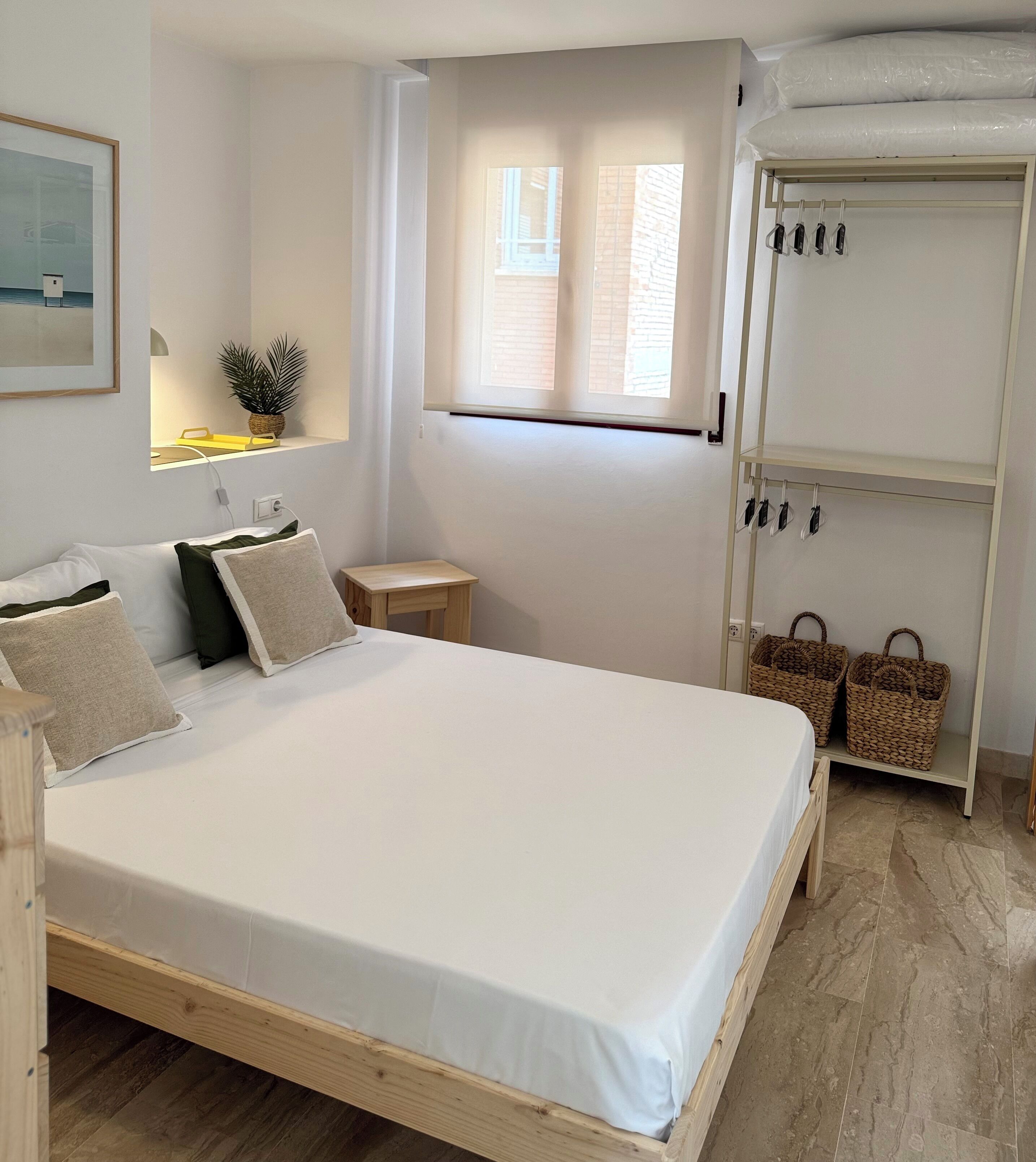 A neatly arranged bedroom with a bed, bedside tables, a window, and a wardrobe.