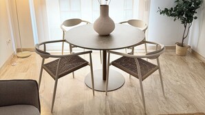 Ein stilvoller Essbereich mit einem runden Tisch, vier Stühlen, einer Blumenvase, einer Stehlampe und einer Topfpflanze.