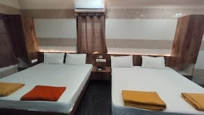 A hotel room with two beds, a nightstand, and an air conditioning unit. - BK Stays (Chirala)