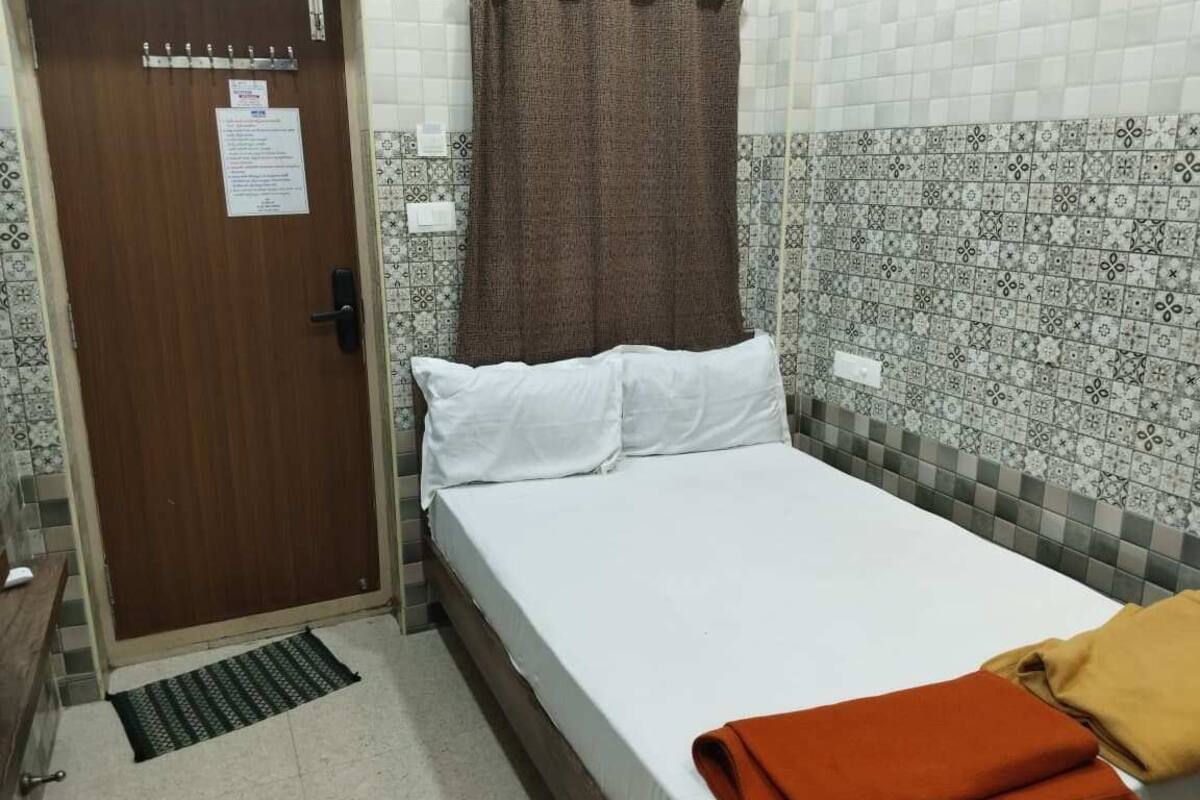 A room with a bed, a door, a curtain, and patterned wall tiles.