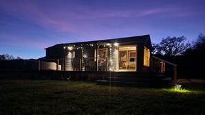 Une maison moderne dotée d’une terrasse, de grandes fenêtres et d’un éclairage extérieur.