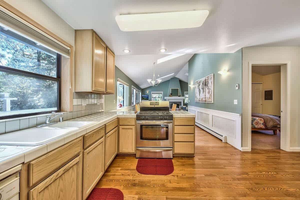 Una cocina con armarios de madera, estufa de acero inoxidable y un ventanal grande.