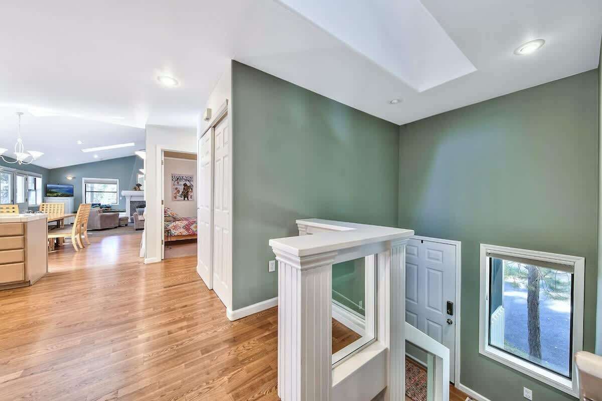 A spacious room with a wooden floor, a white fireplace, and a large window.