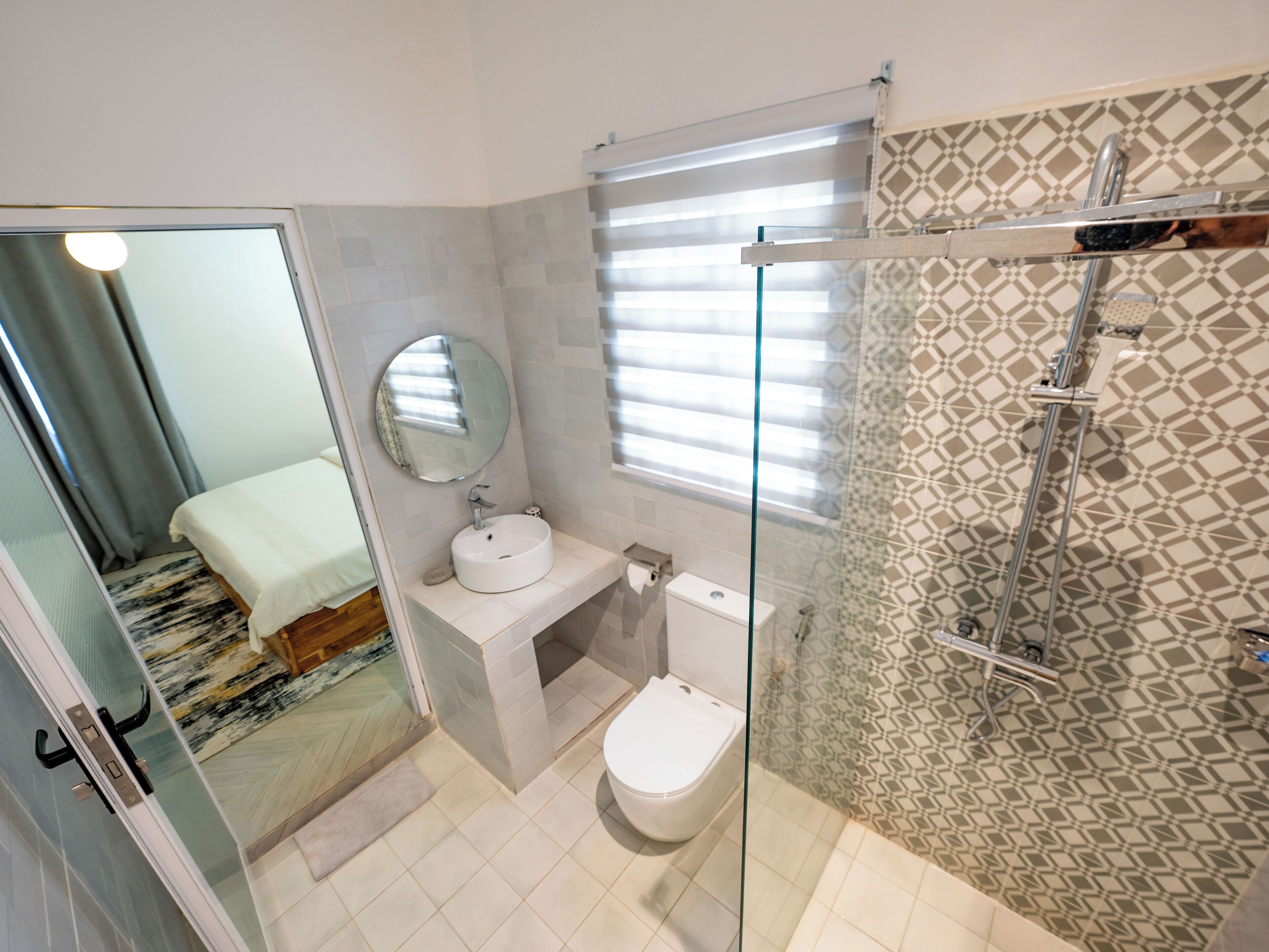 A modern bathroom with a glass shower enclosure, a toilet, and a sink with a mirror.
