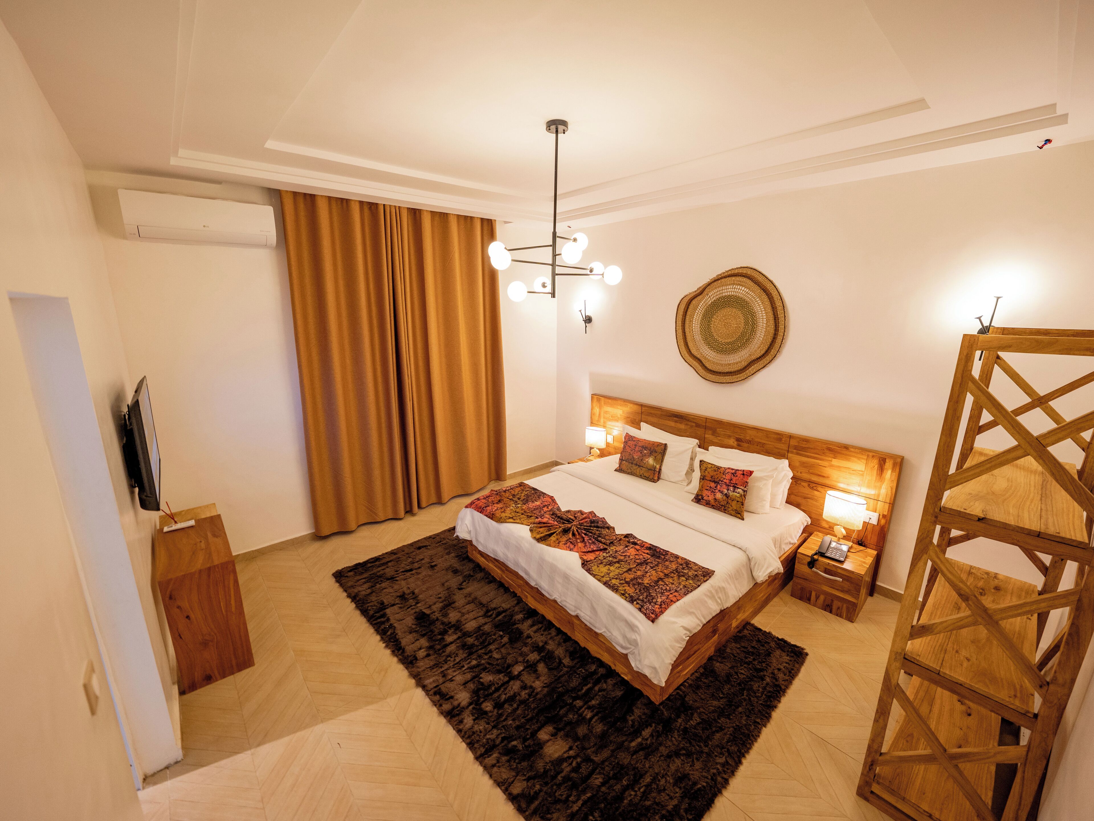 A modern bedroom with a wooden bed, a large rug, a ceiling light, and a wall-mounted air conditioner.