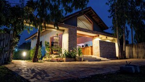 Une maison moderne avec une façade en pierre, une terrasse en bois et une entrée bien éclairée.