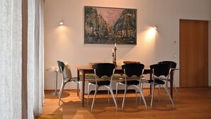 A dining area with a wooden table, four chairs, a painting on the wall, and two wall-mounted lights. - Vacation home with all the amenities (air-conditioned/sauna) (Sternenfels)