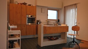 A compact kitchen with wooden cabinets, a built-in oven, a sink, and a kettle. - Vacation home with all the amenities (air-conditioned/sauna) (Sternenfels)