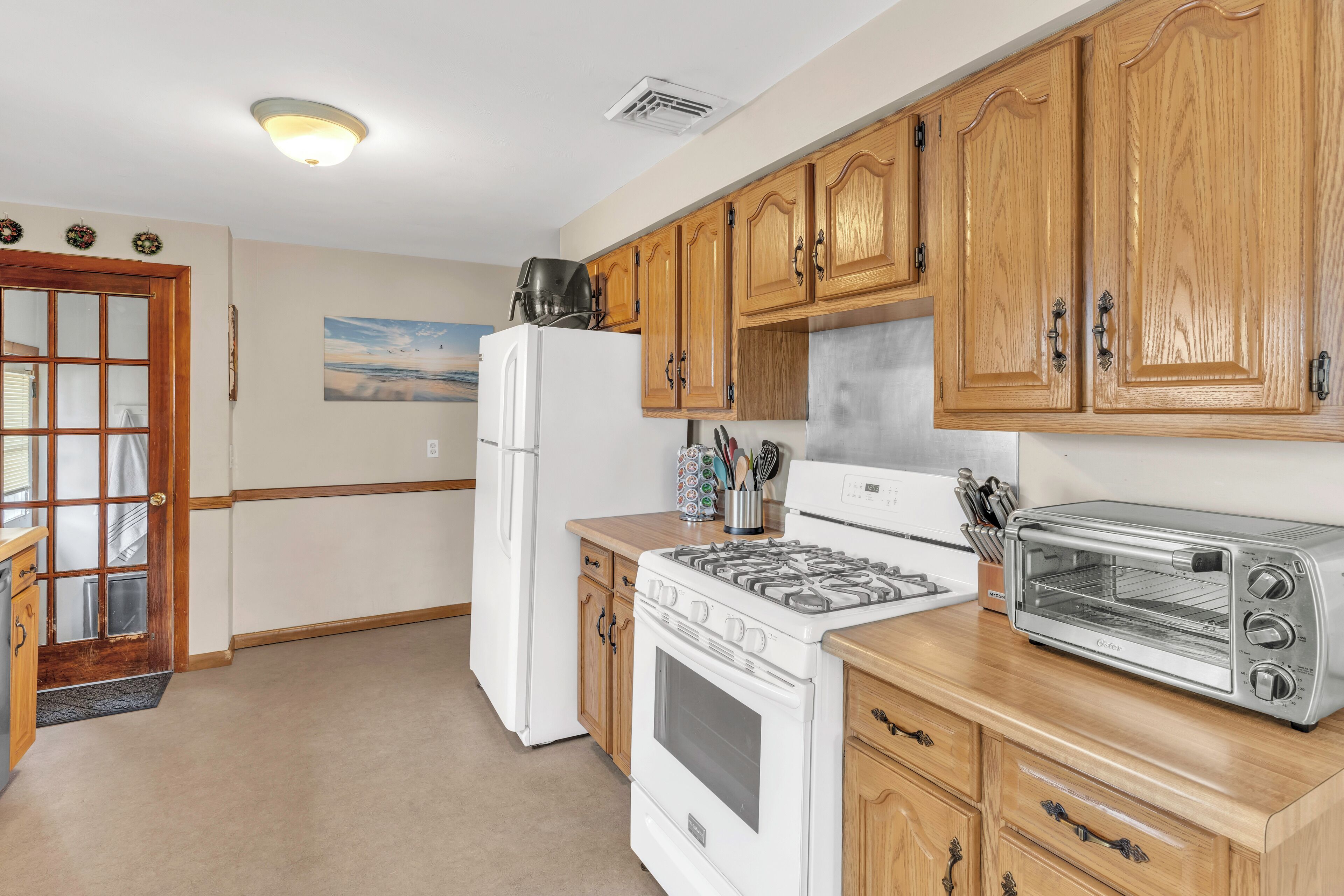 A kitchen with wooden cabinets, a white refrigerator, a stove, and a toaster oven.