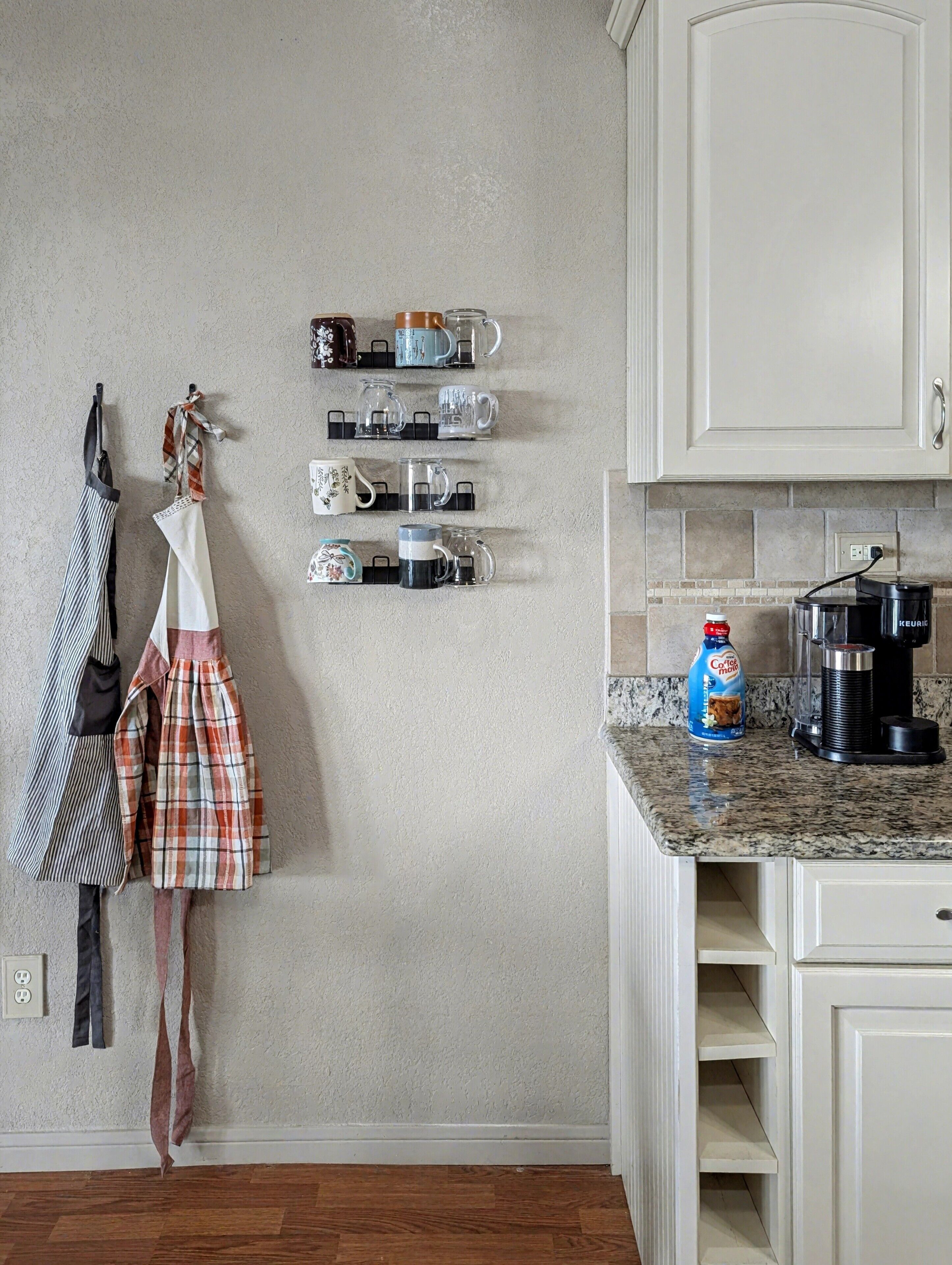 Una cocina con armarios blancos, una cafetera y una botella de leche para café sobre la encimera.