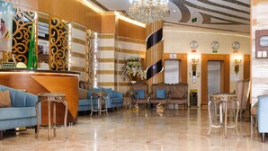 A hotel lobby with a reception desk, blue sofas, and a chandelier. - Saraya Abeer Hotel Company (Makkah)