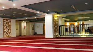 A spacious indoor area with a red carpeted floor leading to a door. - Saraya Abeer Hotel Company (Makkah)