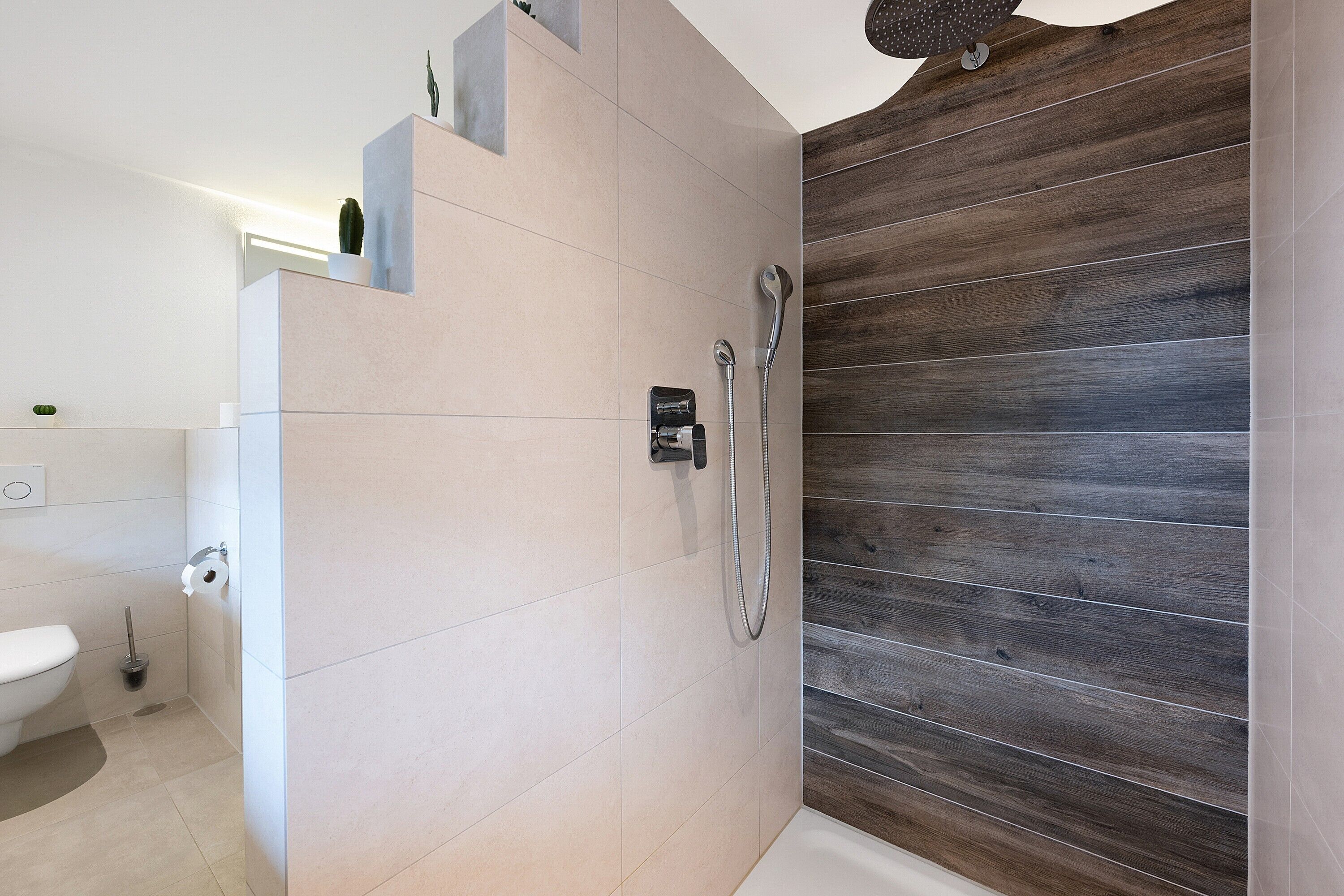 Ein modernes Badezimmer mit Dusche, Toilette und einer Wandpaneele aus Holz.