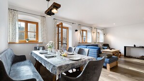 Un coin repas avec une table dressée pour quatre personnes, un canapé bleu et une cheminée.