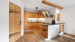 Une cuisine avec des meubles de rangement en bois, un îlot central et un luminaire au plafond.