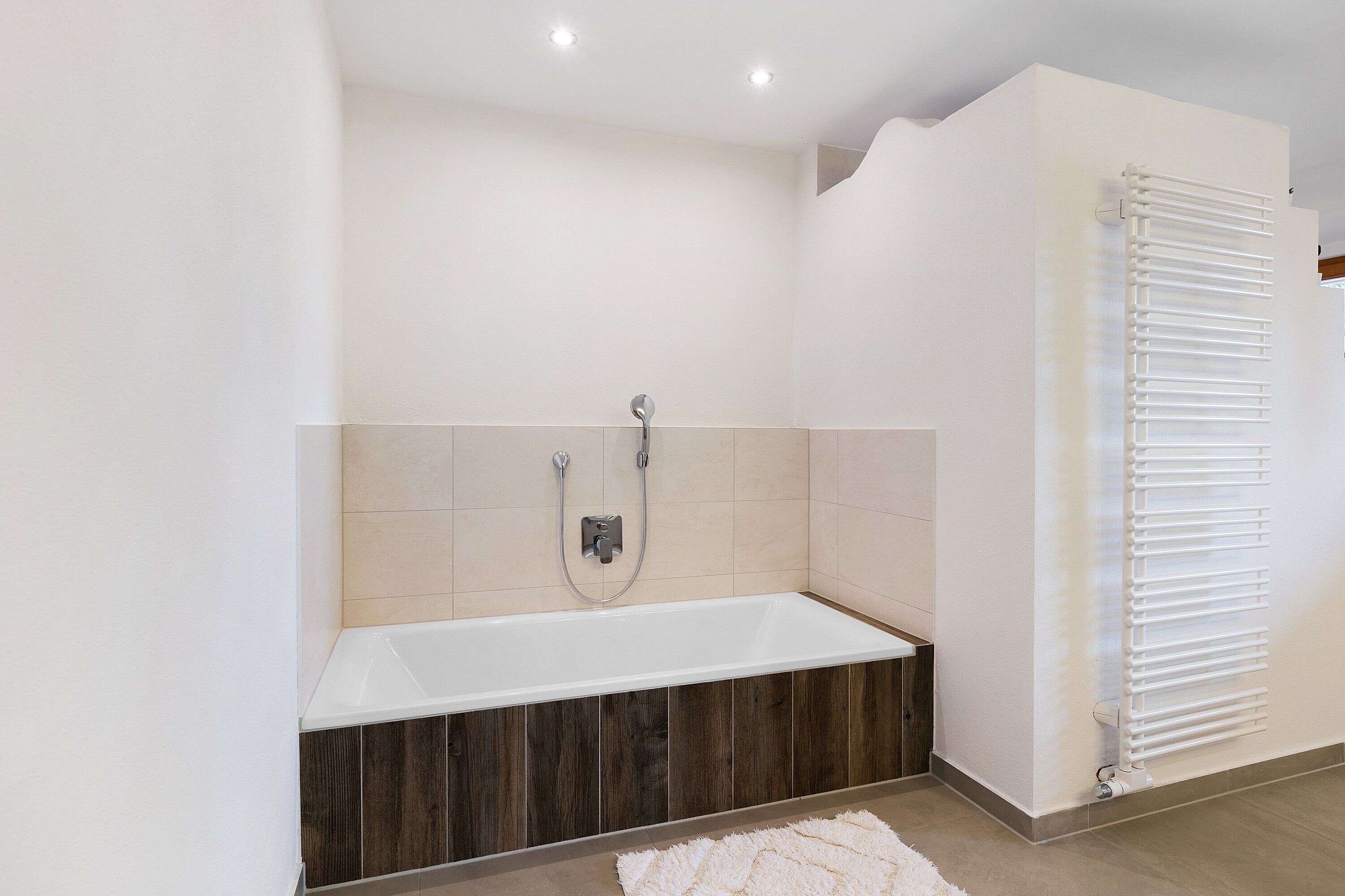 Une salle de bain moderne équipée d’une baignoire, d’une douche et d’un radiateur.